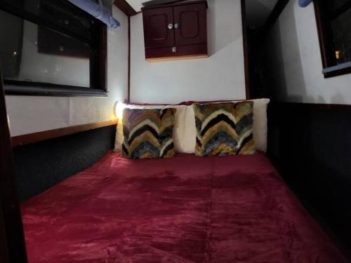 a room with two pillows and a red carpet at Comfy Canal Boat in London Centre Family & Friends in London