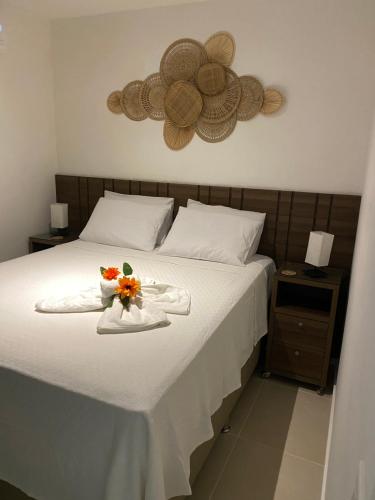 a bed with a tray of flowers and hats on it at Morada do Sol Flat in Morro de São Paulo