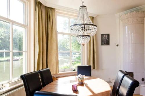 a dining room with a table and chairs and a chandelier at Historical house on river Vecht in Maarssen