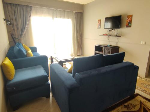 a living room with two blue couches and a television at Luxury Host -219- Dream Land in 6th Of October