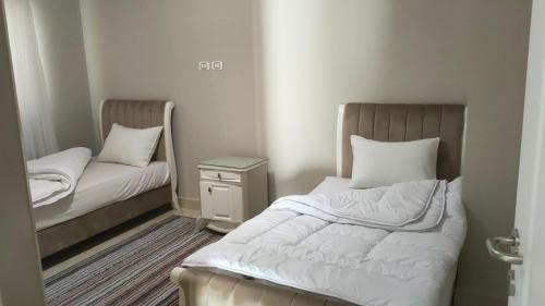 a small room with two beds and a night stand at Luxury Host -219- Dream Land in 6th Of October