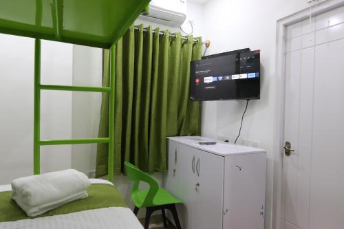 a bedroom with a green curtain and a bed and a television at Athulya Stays in Bengaluru