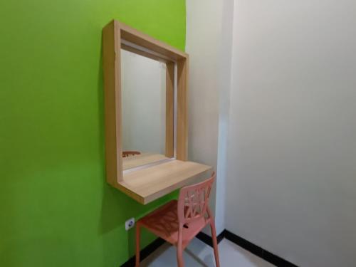 een badkamer met een spiegel en een roze stoel bij The Cabin Hotel Ngupasan in Yogyakarta