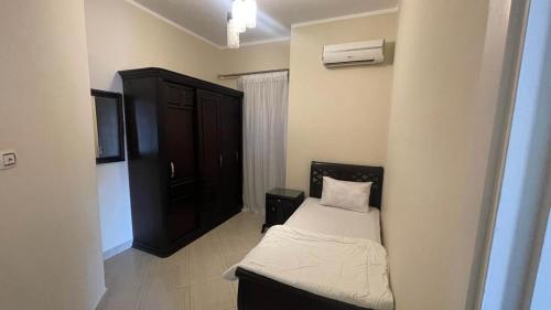 a small bedroom with a bed and a black cabinet at Luxury Host -219- Dream Land in 6th Of October