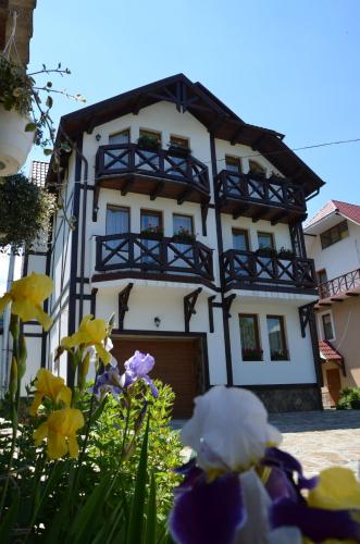 a white and black building with flowers in front of it at Fachwerk in Yaremche