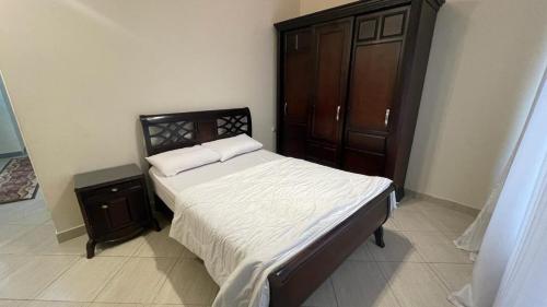 a bedroom with a bed and a wooden cabinet at Luxury Host -219- Dream Land in 6th Of October