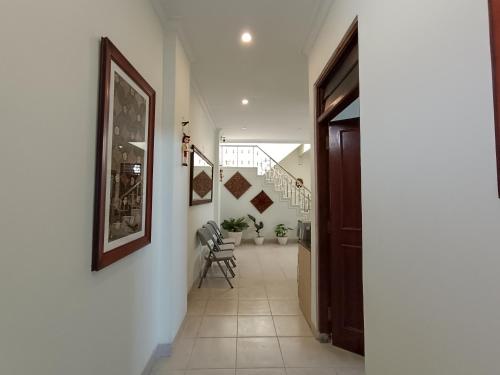 a hallway with white walls and a staircase with chairs at The Cabin Hotel Ngupasan in Yogyakarta