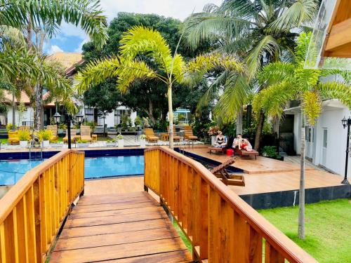 a wooden walkway leading to a swimming pool with palm trees at White Land City Hotel in Dambulla
