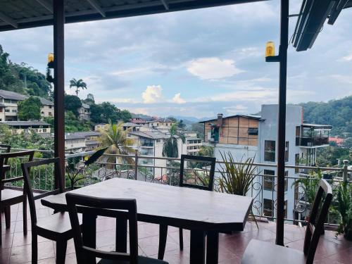 a table and chairs on a balcony with a view at Sakura hotel and restaurant in Kandy