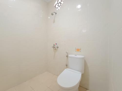 a white bathroom with a toilet and a faucet at The Cabin Hotel Ngupasan in Yogyakarta