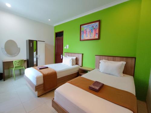 een kamer met 2 bedden en een groene muur bij The Cabin Hotel Ngupasan in Yogyakarta