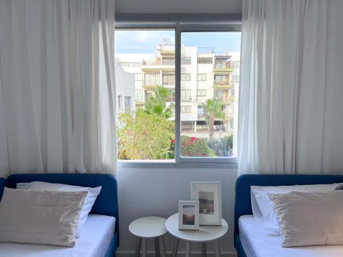 a room with two beds and a large window at Daimond Complex Sea View Apartment in Paphos