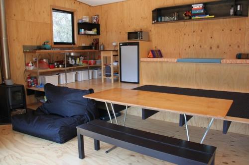 a living room with a table and a couch at BAY OF FIRES ECO HUT off grid experience at Binalong Bay in Binalong Bay