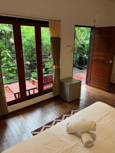 a bedroom with a bed and a sliding glass door at Seafront Jungle Bungalow in Koh Phangan