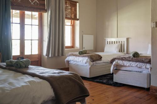 a bedroom with two beds and two windows at The Border Post, Bed and Breakfast in Bergville