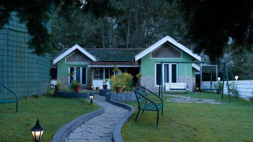 a green house with a bench in the yard at The Green Casa - Families Only in Ooty