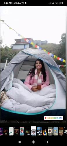 a woman sitting in a bed in a tent at TEC Resort and bar in Dharān Bāzār