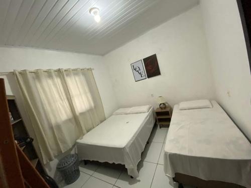two beds in a small room with a window at Rochedo Casa de Praia in Nova Viçosa
