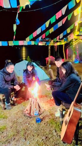 a group of three people sitting around a fire at TEC Resort and bar in Dharān Bāzār