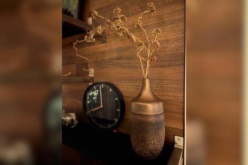 ロヴァニエミにあるLapland city apartmentの時計の横に植物を入れた花瓶