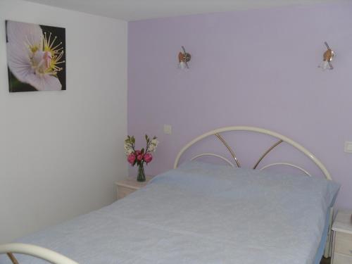 um quarto com uma cama branca e uma fotografia de uma flor em T2 Lamalou près de la nature. em Lamalou-les-Bains