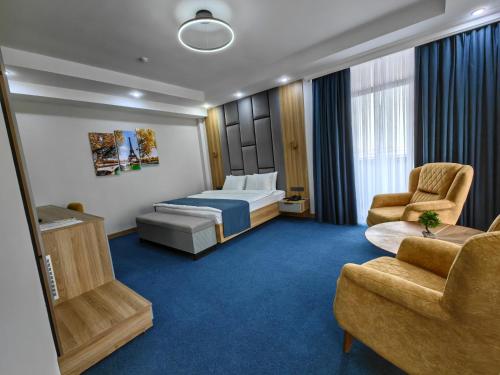 a hotel room with a bed and two chairs at Shymkent Park Hotel in Shymkent