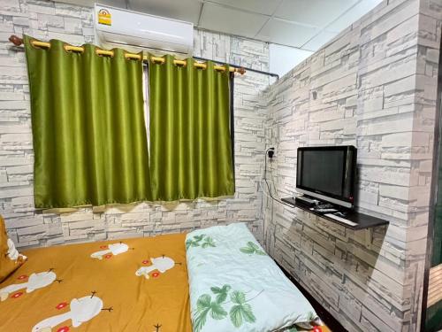 um quarto com uma cortina verde e uma televisão em Natcha Place Rangsit Donmuang em Ban Talat Rangsit