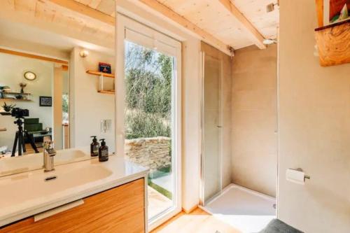 a bathroom with a tub and a sink and a window at Tinyhouse Minimalus Panorama Schlafloft im Grünen in Dessighofen
