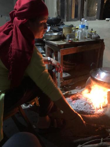 a woman is cooking food over a fire at Tharu Community Home Stay in Chitwan