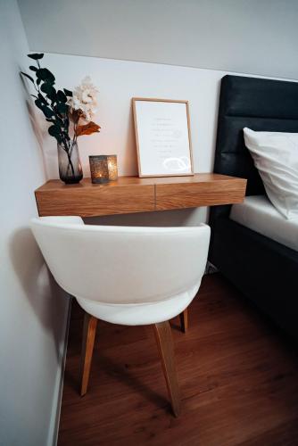 a white chair with a wooden table next to a bed at Jamy House in Habovka