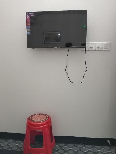 a television hanging on a wall with a red stool at Hotel In Need - Near to the US France Italy Saudi Embassy and Airport in Dhaka
