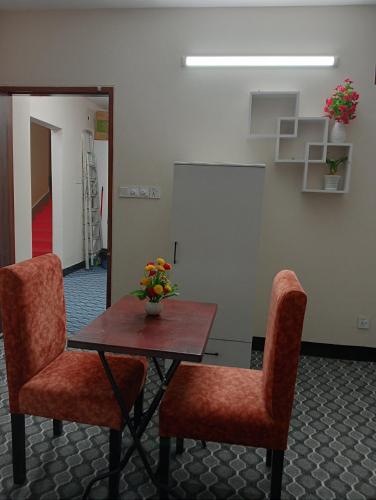 a table with two chairs and a table with flowers on it at Hotel In Need - Near to the US France Italy Saudi Embassy and Airport in Dhaka