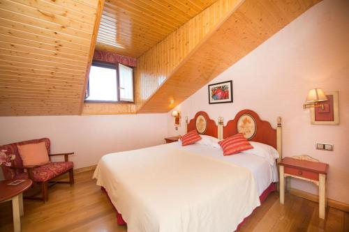 a bedroom with a large white bed in a attic at Hospederia La Cañada in Moralzarzal