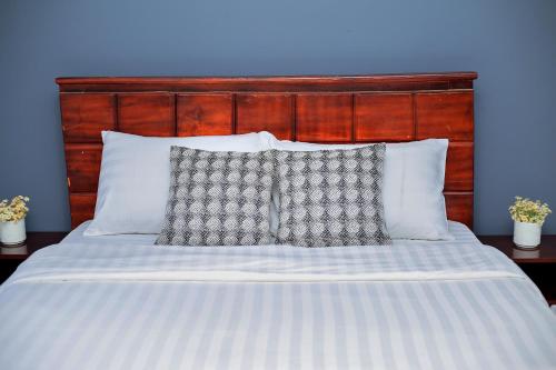 a bed with a wooden head board and two pillows at Pearl Sanctuary 01 Kiwatule, Kampala in Kira