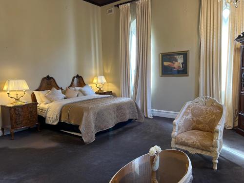 a bedroom with a bed and a chair and a table at Convent at Koroit in Koroit