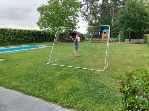 a man is playing with a net in a yard at vakantiewoning met permanent verwarmd zwembad en sauna in Koekelare