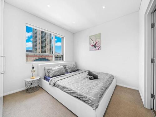 a white bedroom with a bed and a window at Lovely Apartment in the heart of Chinatown in Sydney