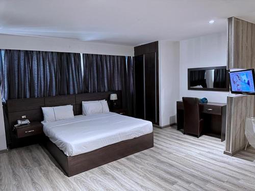 Dormitorio con cama, escritorio y TV en Saraya Al Joude en Irbid