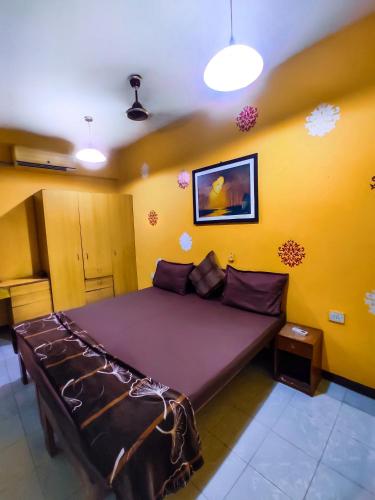 a bedroom with a large bed in a yellow room at Alor Elite Flats in Calangute