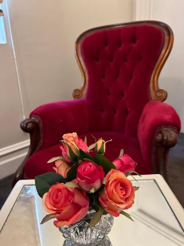 a vase of roses sitting on a table next to a chair at Convent at Koroit in Koroit