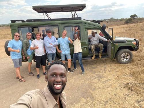 eine Gruppe von Menschen steht vor einem grünen Fahrzeug in der Unterkunft KABA Local Rwandan Guesthouse Entire Property for you with Tour services in and out the city such as Safari's in Kigali