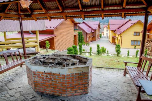 a brick fireplace on a patio with two benches at Schale Centoriya in Mykulychyn