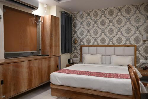 THE M K HOTEL -Luxury In Style في Chās: غرفة نوم بسرير وتلفزيون بشاشة مسطحة