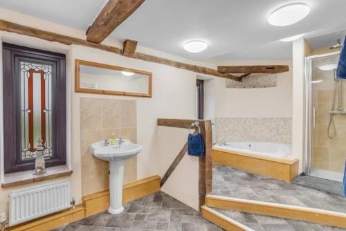 a bathroom with a sink and a bath tub at amazing barn conversion with hot tub in North Walsham