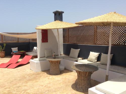 un patio con sillas, mesas y sombrillas en Dar Les Sirènes, en Essaouira
