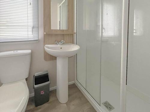 a white bathroom with a toilet and a sink at Beautiful 8 Berth Caravan With Decking At Naze Marine Park, Essex Ref 17184p in Walton-on-the-Naze