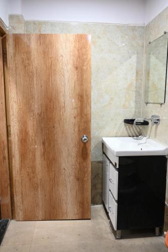La salle de bains est pourvue d'une porte en bois et d'un lavabo. dans l'établissement THE M K HOTEL -Luxury In Style, à Chās