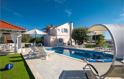 a pool with chairs and umbrellas next to a house at Nice Home In Stratincica With Wifi in Vela Luka