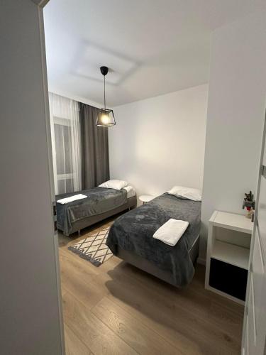 two beds in a small room with a window at Apartament ANNA in Biała Podlaska