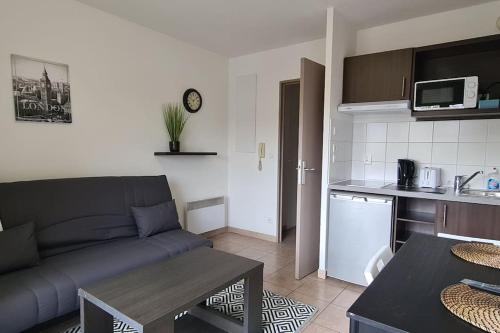 un salon avec un canapé et une cuisine dans l'établissement B210 Appartement DisneyLand Paris Parking et wifi, à Montévrain